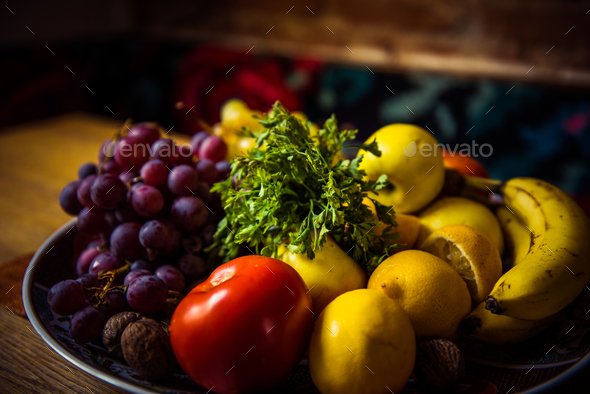 Mix of delicious fruits in a plate on a wooden table