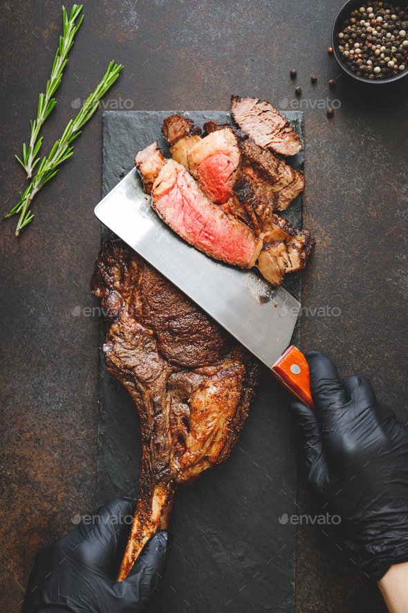 Man in black gloves cuts dry-aged marble beef steak Tomahawk. Top view, dinner concept.