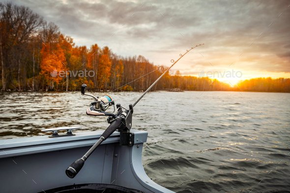 Fishing rod on the boat, sunset time. Beautiful autumn colors. A fishing rod is a long, flexible rod used by fishermen to catch fish.